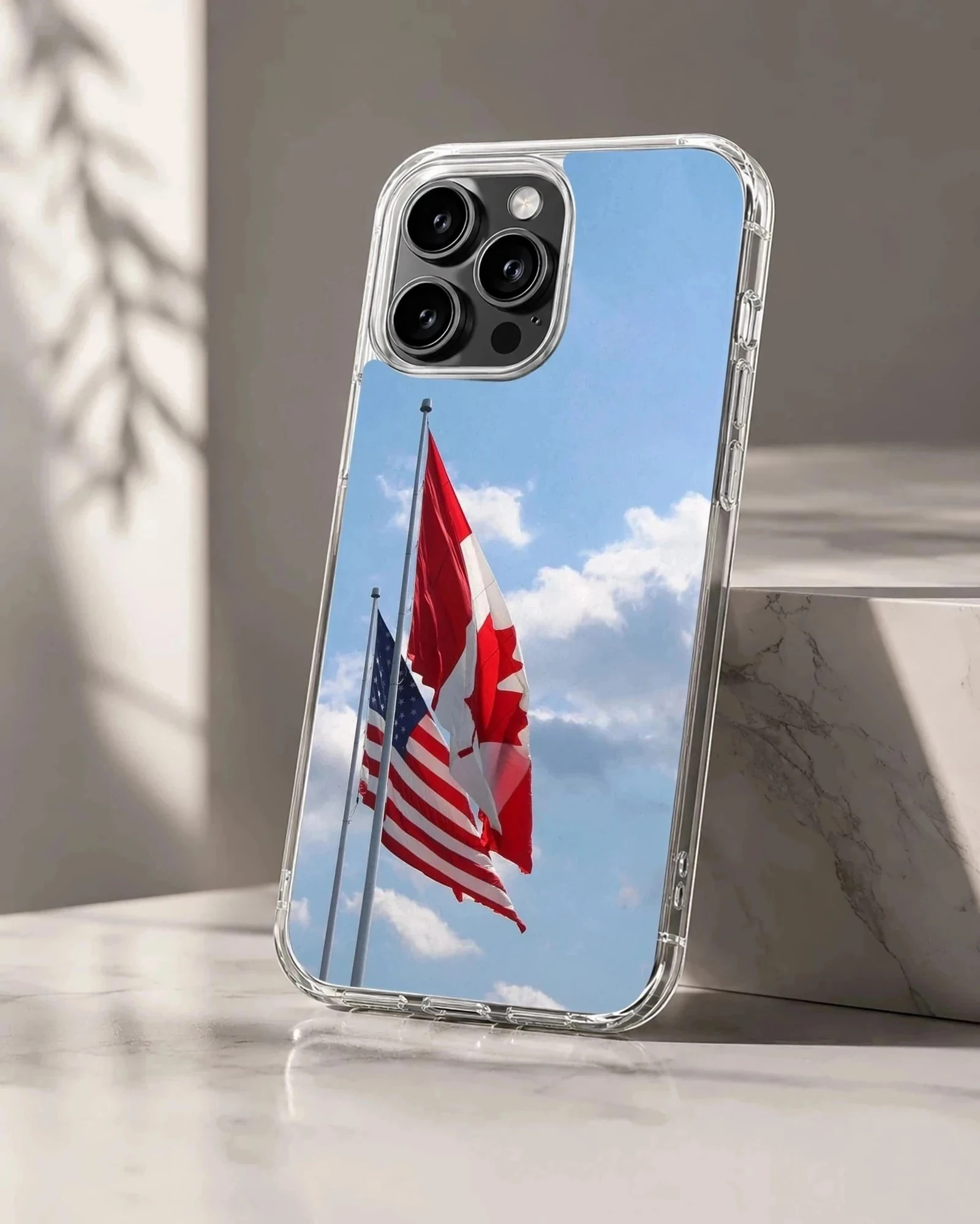 Canadian and American flags waving against a bright blue sky on a phone case