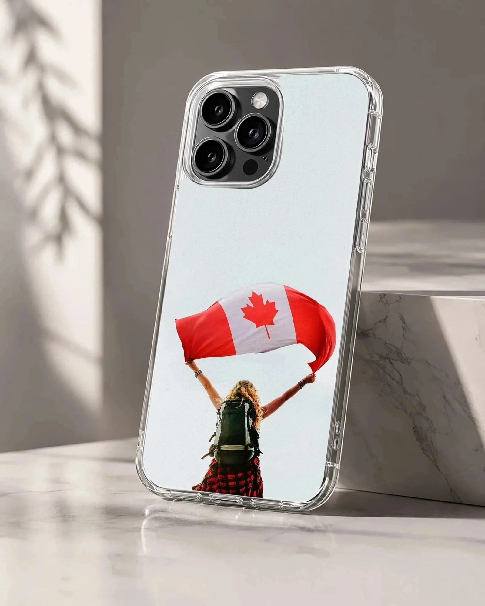 A hiker with a backpack holds up a waving Canadian flag against a pale sky on a phone case