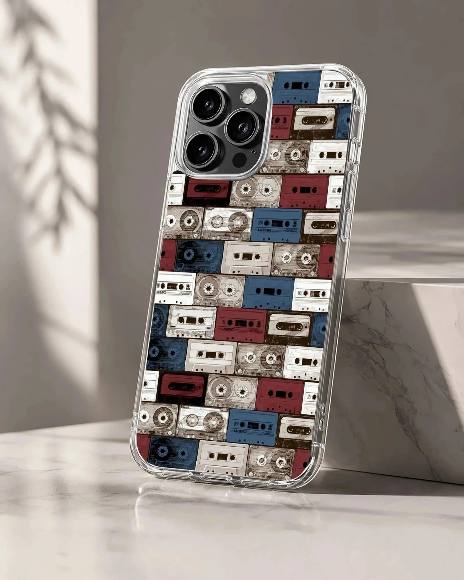 A patterned phone case featuring a collage of vintage cassette tapes in red, white, and blue hues.