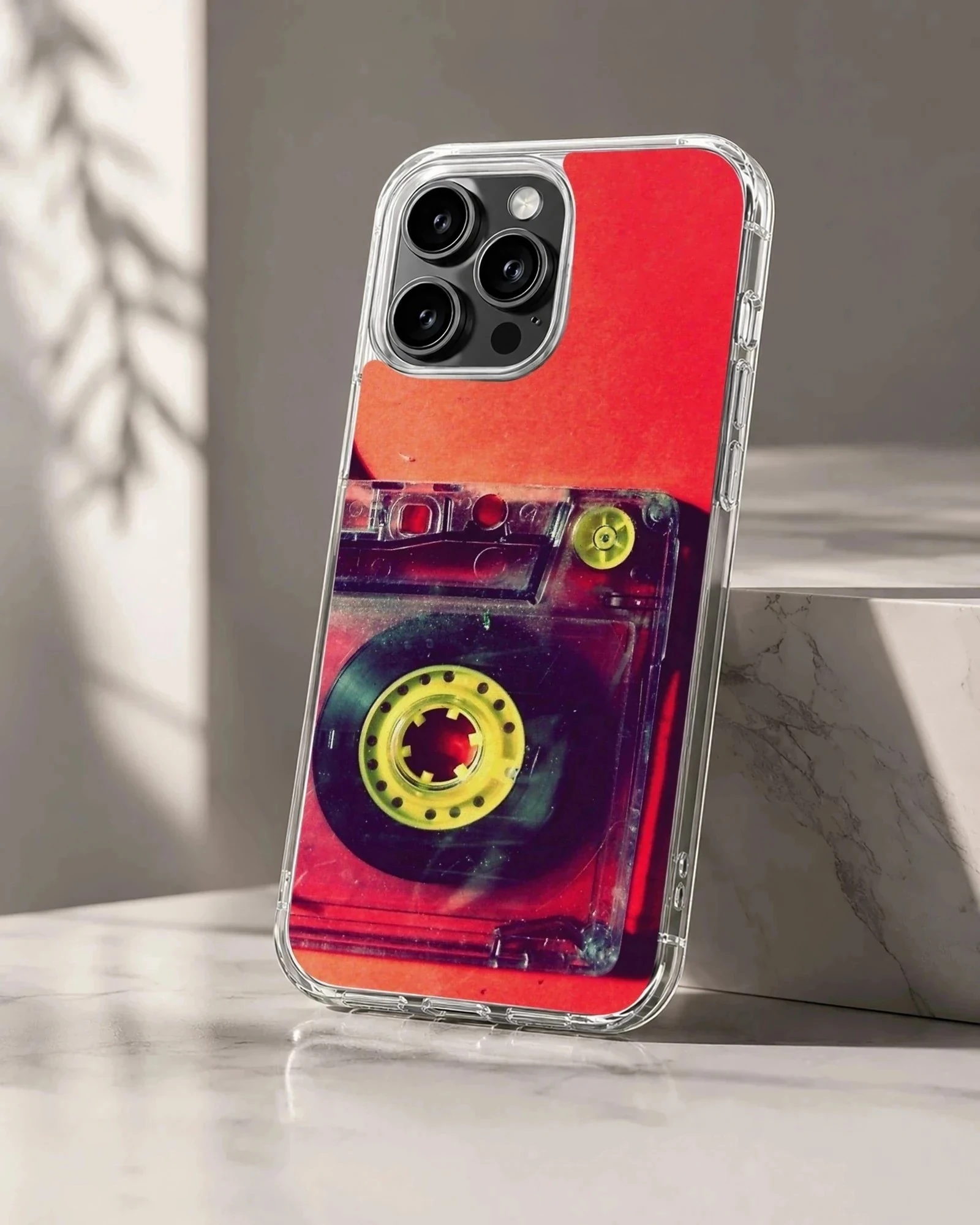 Close-up photograph of a vintage translucent red cassette tape with yellow reels on a phone case