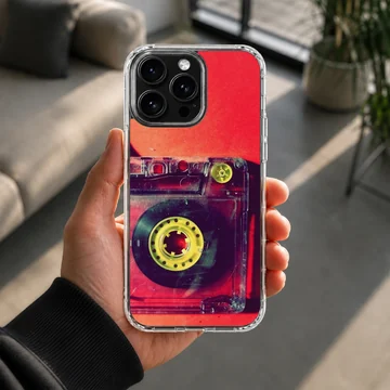 Close-up photograph of a vintage translucent red cassette tape with yellow reels on a phone case — Lifestyle