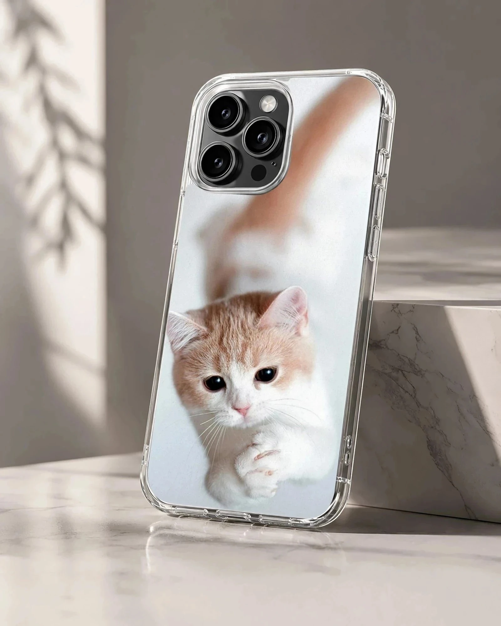 Close-up photographic print of a ginger and white kitten looking up with cute paws on a phone case