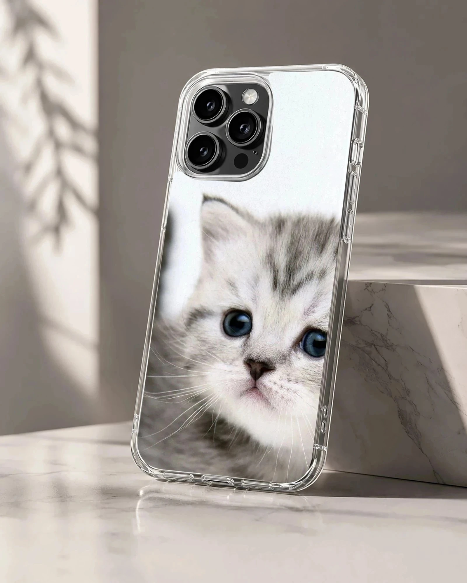 Close-up photographic print of a fluffy grey kitten with wide blue eyes on a phone case