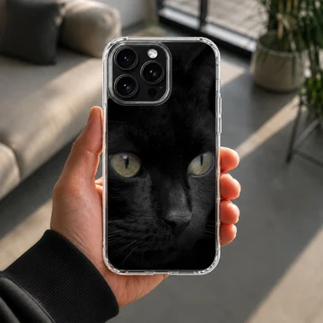 Close-up portrait of a sleek black cat with glowing green-yellow eyes printed on a phone case — Lifestyle