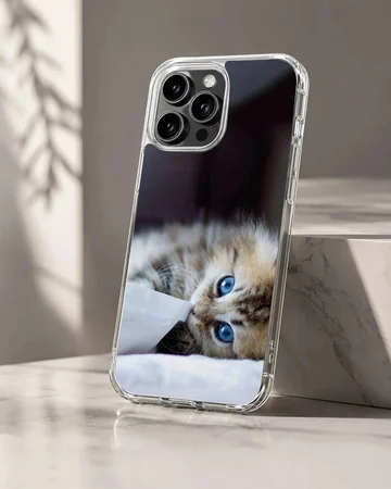 A fluffy kitten with striking blue eyes peeking from under a white blanket on a phone case