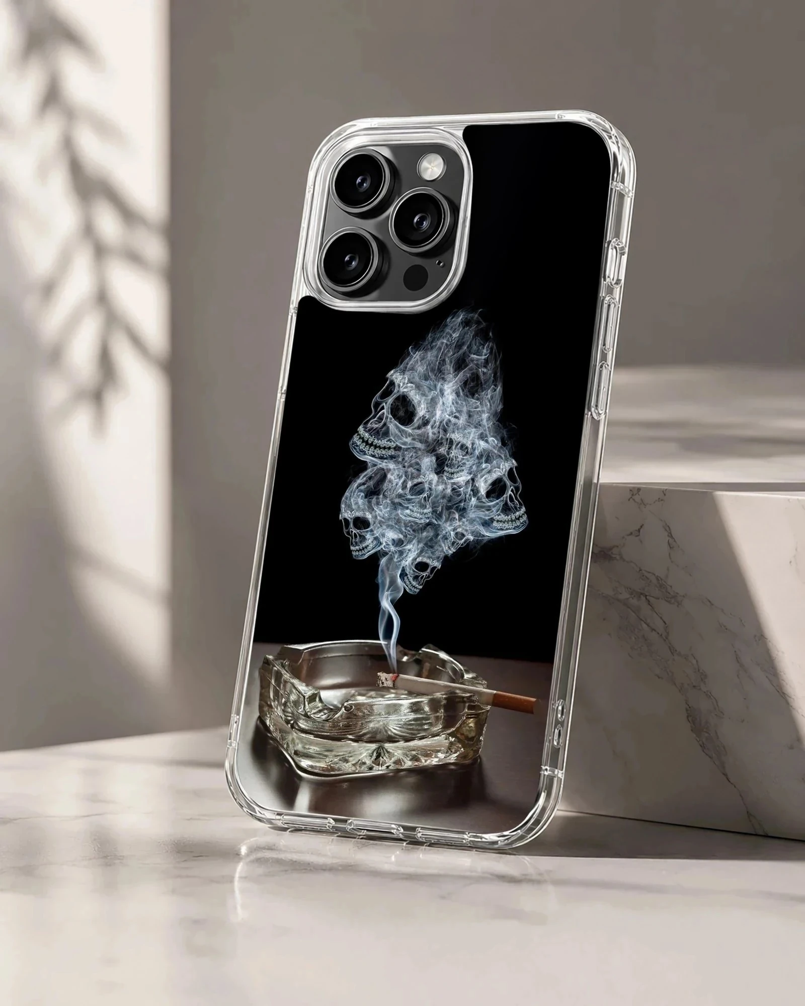 A dark phone case design featuring wisps of smoke forming skulls rising from an ashtray phone case