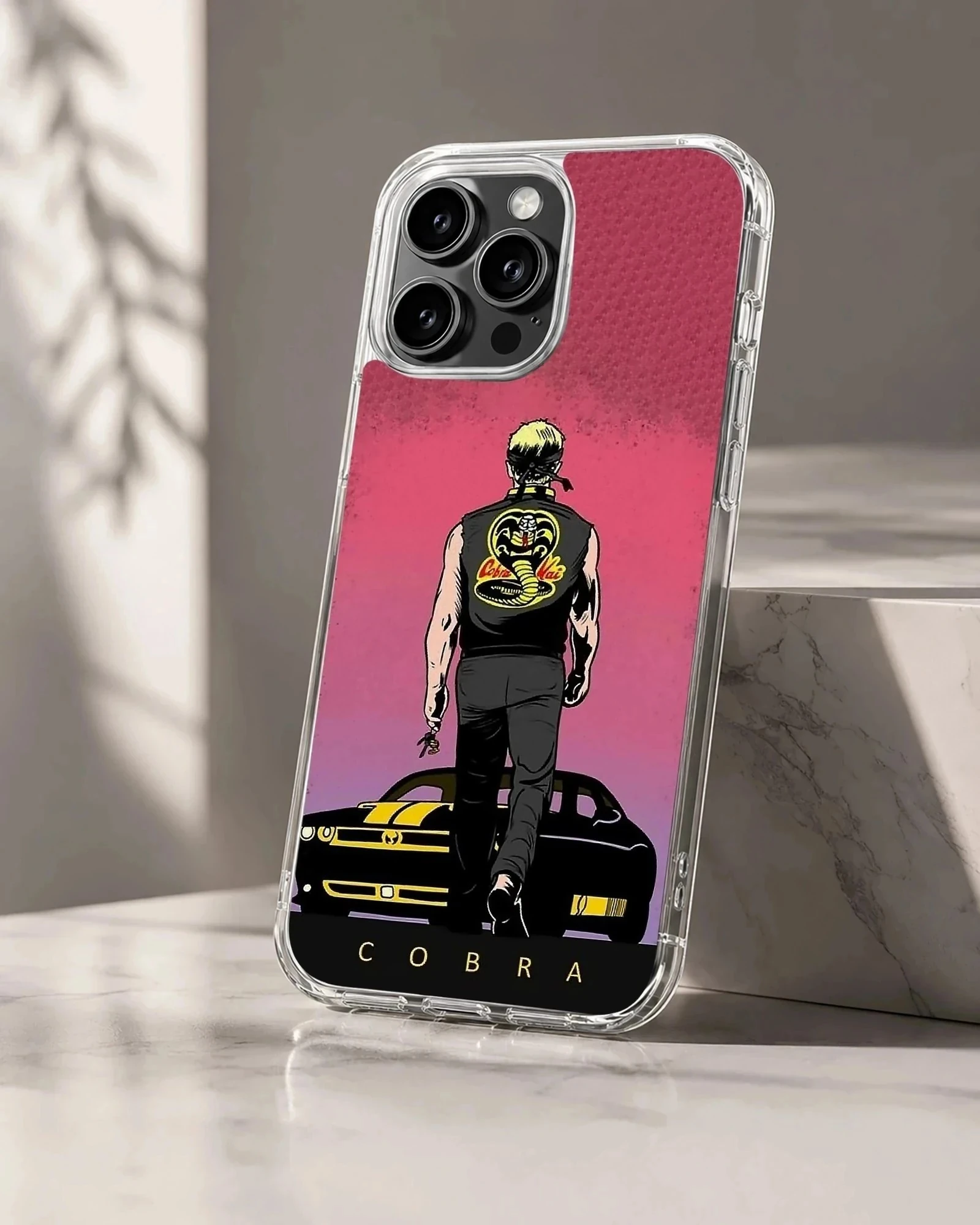 Illustrated graphic of a martial artist walking toward a muscle car under a pink sky on a phone case