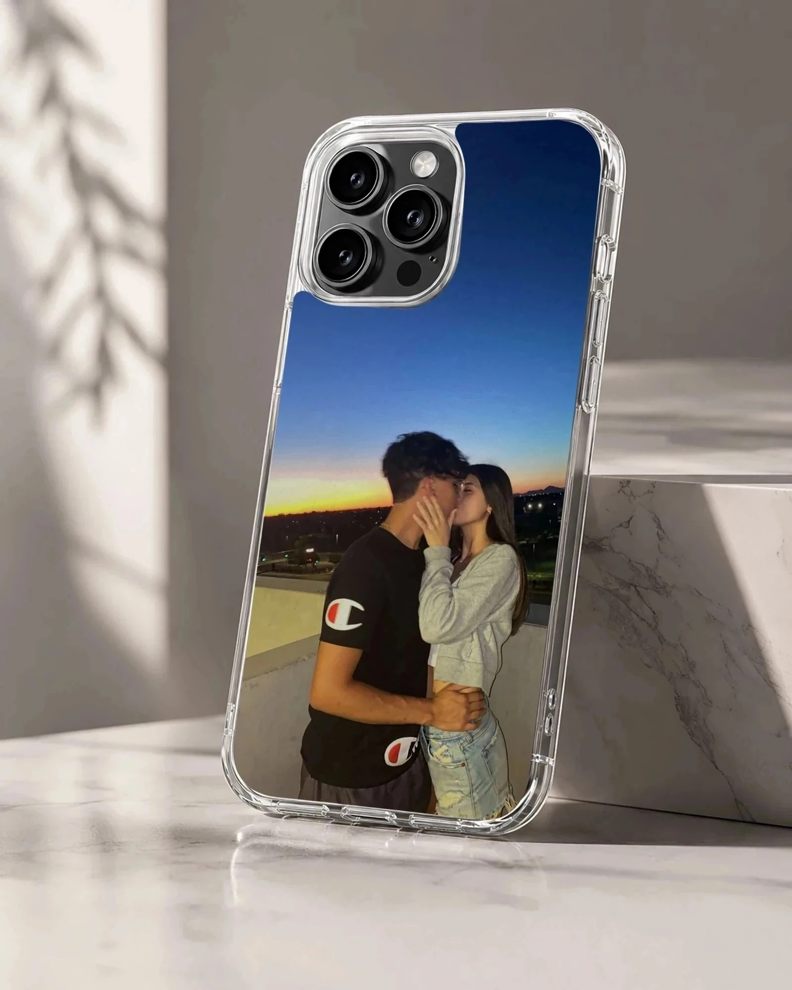 Photographic print of a young couple kissing against a vibrant sunset sky on a snap phone case.