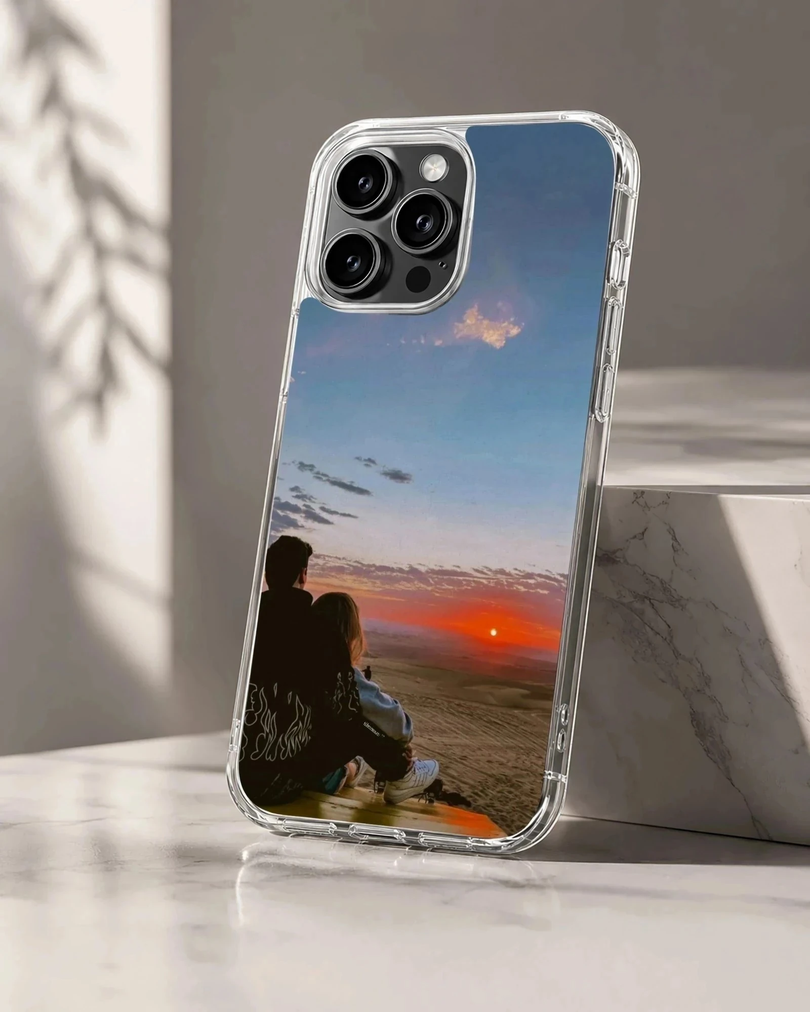 Silhouette of a couple sitting together watching a vibrant orange sunset on a romantic phone case.