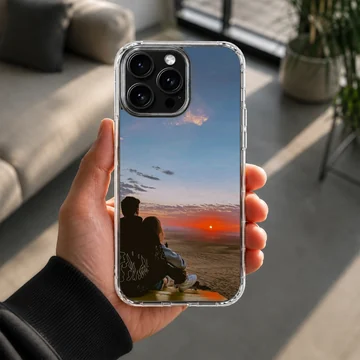 Silhouette of a couple sitting together watching a vibrant orange sunset on a romantic phone case. — Lifestyle