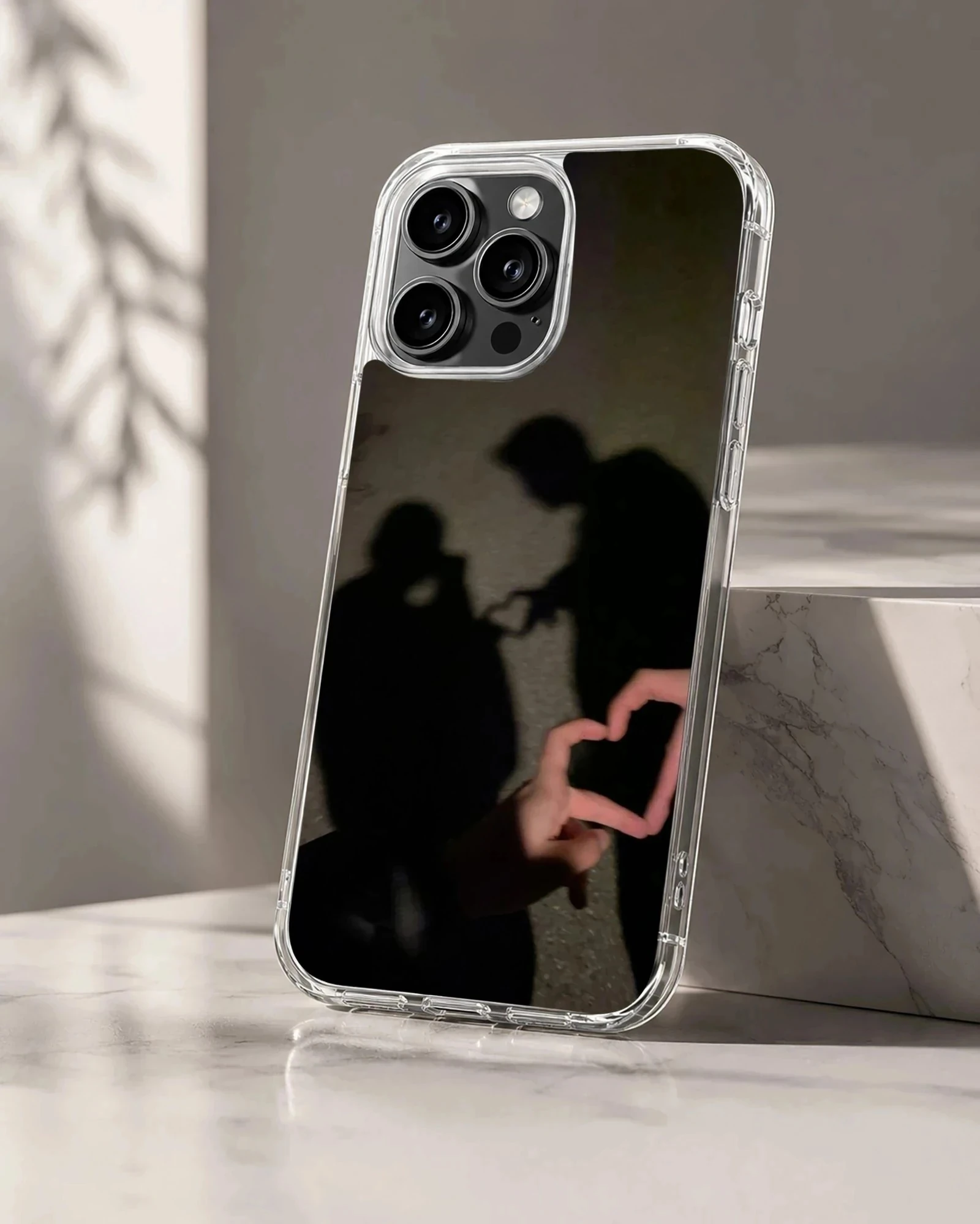 A photographic print of a couple's shadow forming a heart shape, featured on a matte phone case.