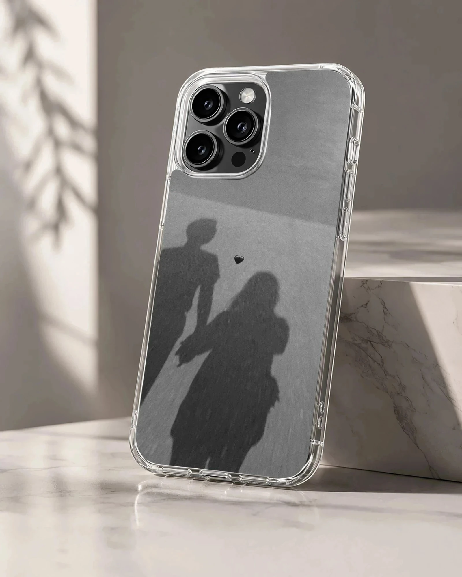 Shadow silhouette of a couple holding hands with a small floating heart, printed on a matte monochrome phone case.