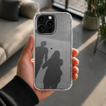 Shadow silhouette of a couple holding hands with a small floating heart, printed on a matte monochrome phone case. — Lifestyle