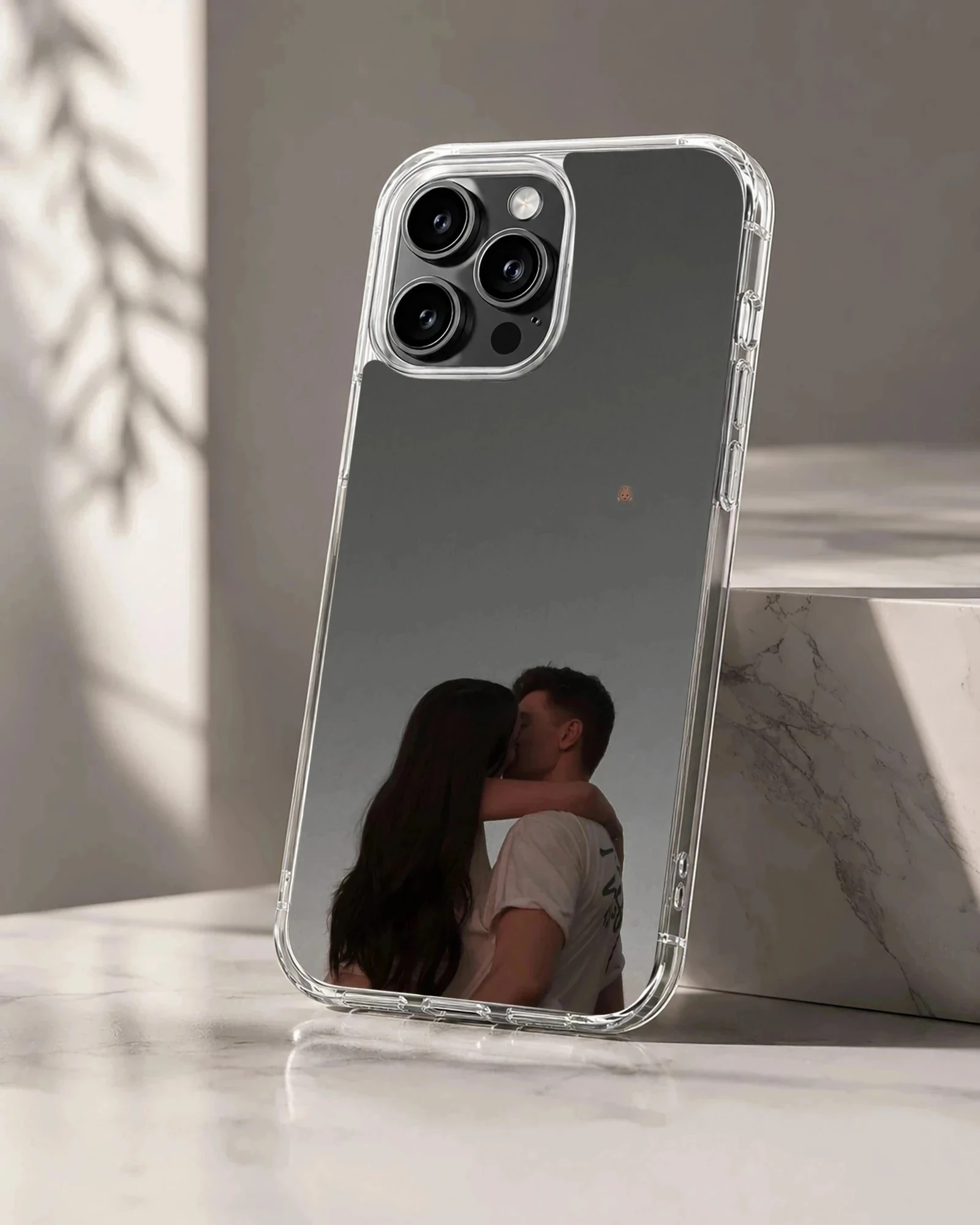 A tender photographic print of a kissing couple embracing against a moody gray sky printed on a protective phone case.