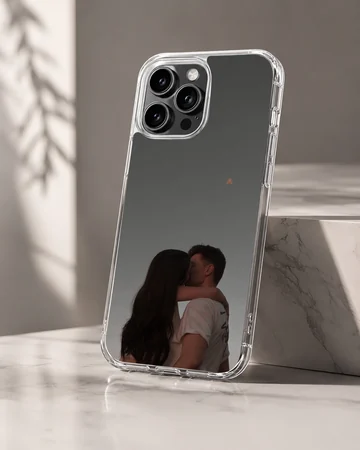 A tender photographic print of a kissing couple embracing against a moody gray sky printed on a protective phone case. — Hero