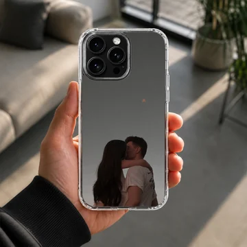A tender photographic print of a kissing couple embracing against a moody gray sky printed on a protective phone case. — Lifestyle