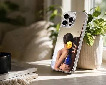 A photograph print on a phone case depicting an embracing couple taking a mirror selfie with a yellow emoji face. — Lifestyle
